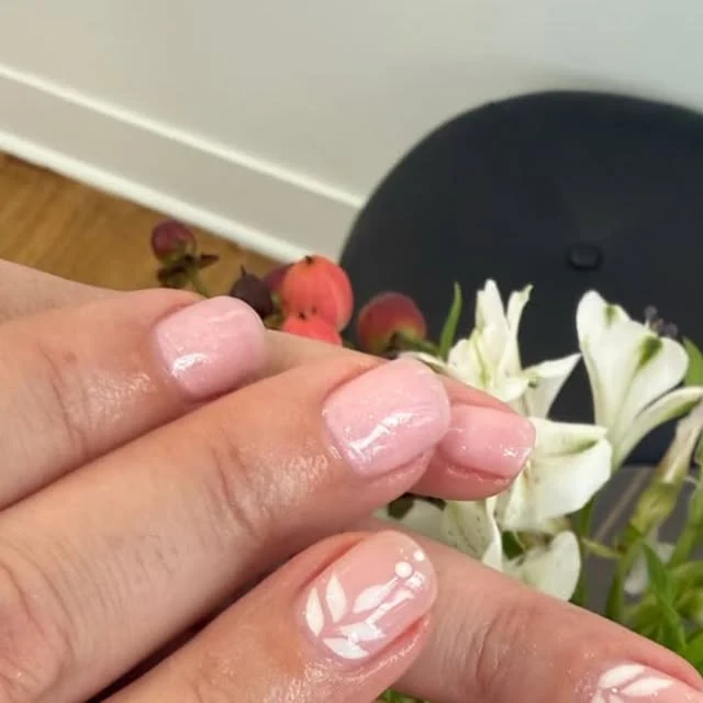 Manucure rose nacré et feuillage blanc délicat.